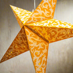 Decorative star-shaped lantern with orange and white pattern on a light blue background