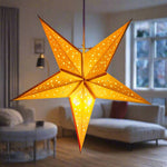 Baby Starry Yellow handmade paper lantern in star shape, glowing warmly in a cosy living room. Eco-friendly lighting for home decor, 42cm diameter.
