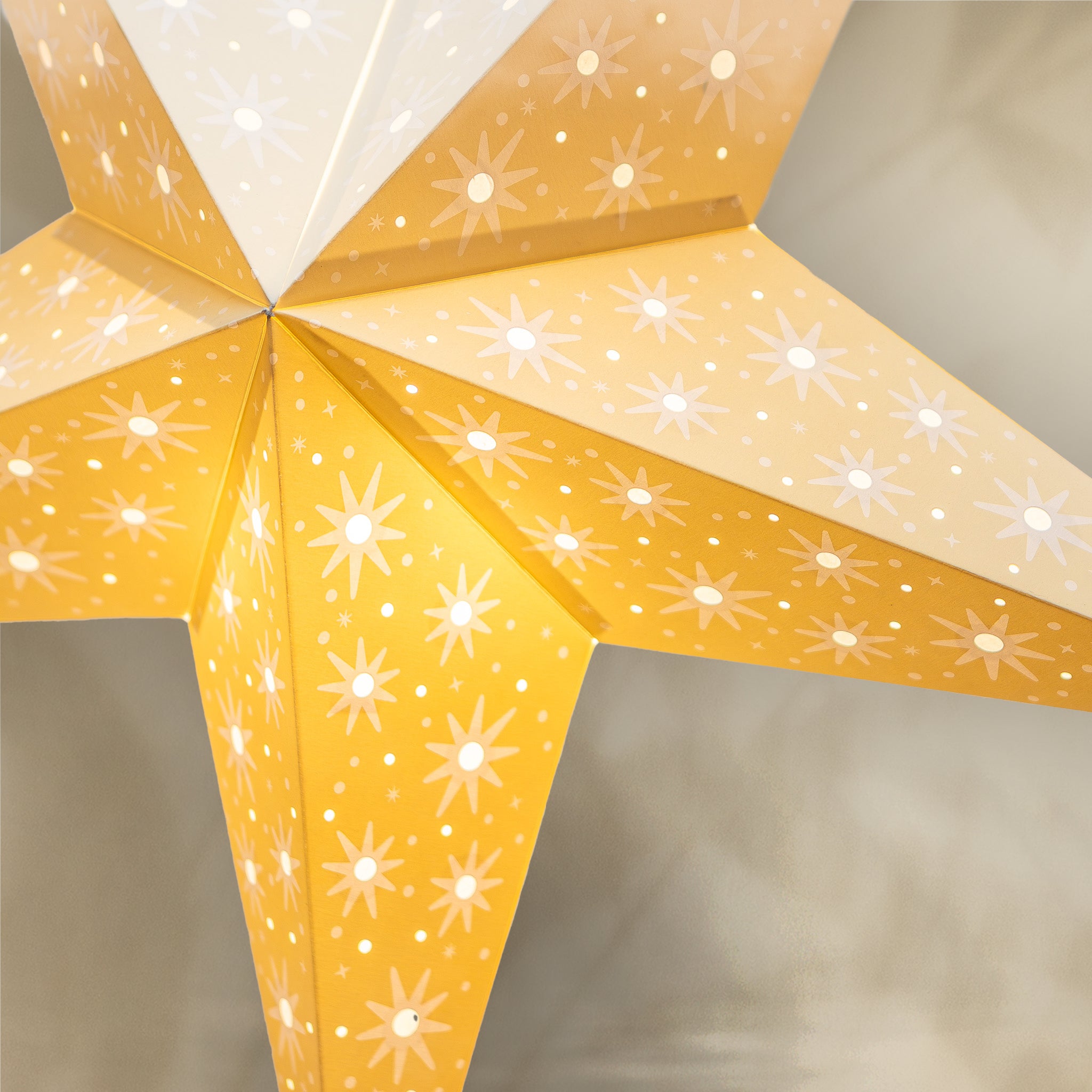 Star-shaped lamp with yellow and white design on a neutral background