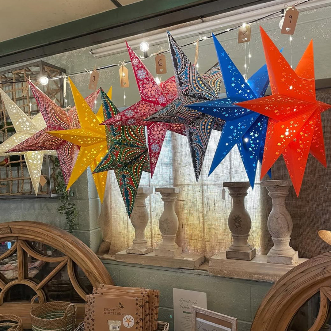 Colorful star-shaped lanterns hanging indoors with decorative elements in the background.