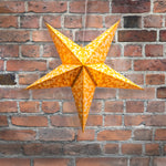 Star-shaped lantern with a pattern hanging on a brick wall