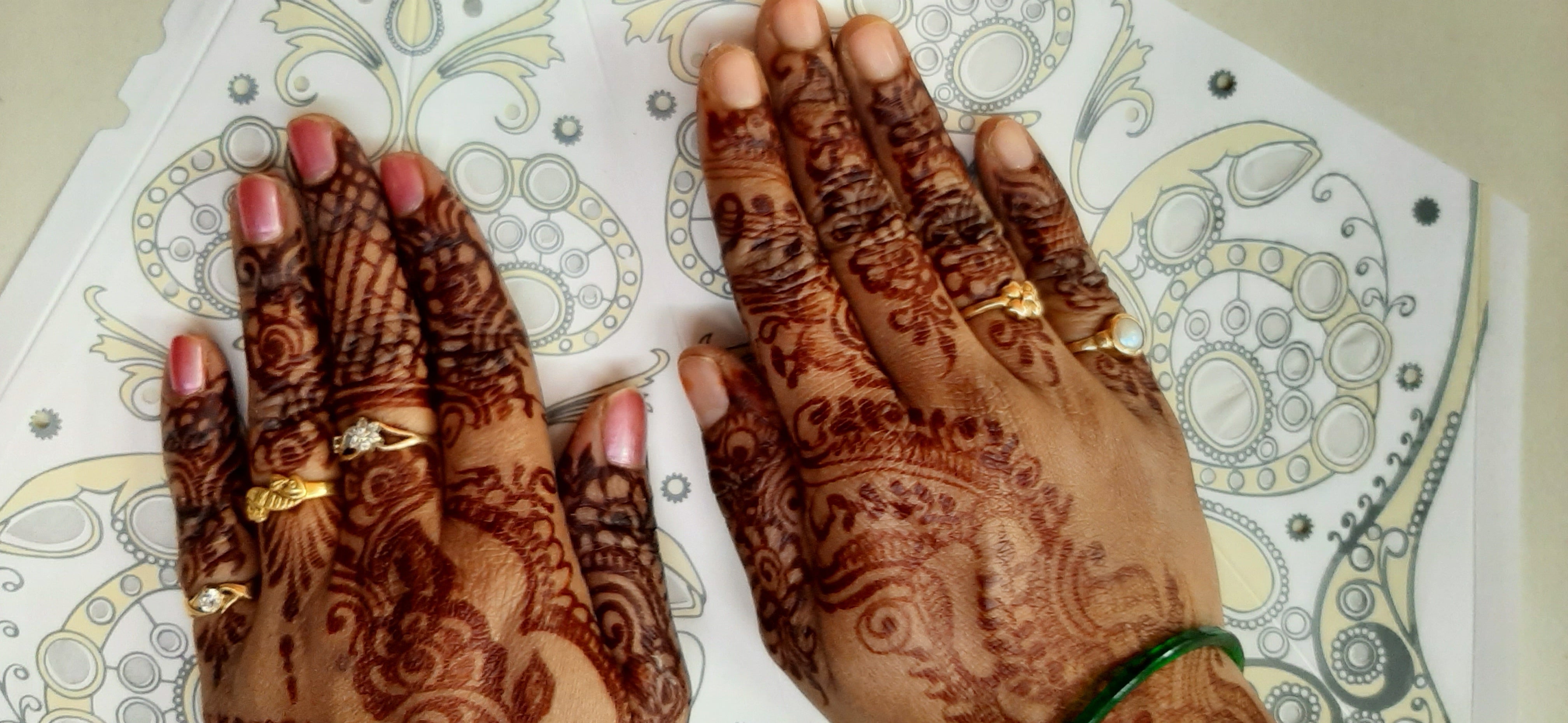 Hands with intricate henna designs on a patterned background