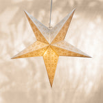Star-shaped paper lantern with cut-out patterns on a beige background