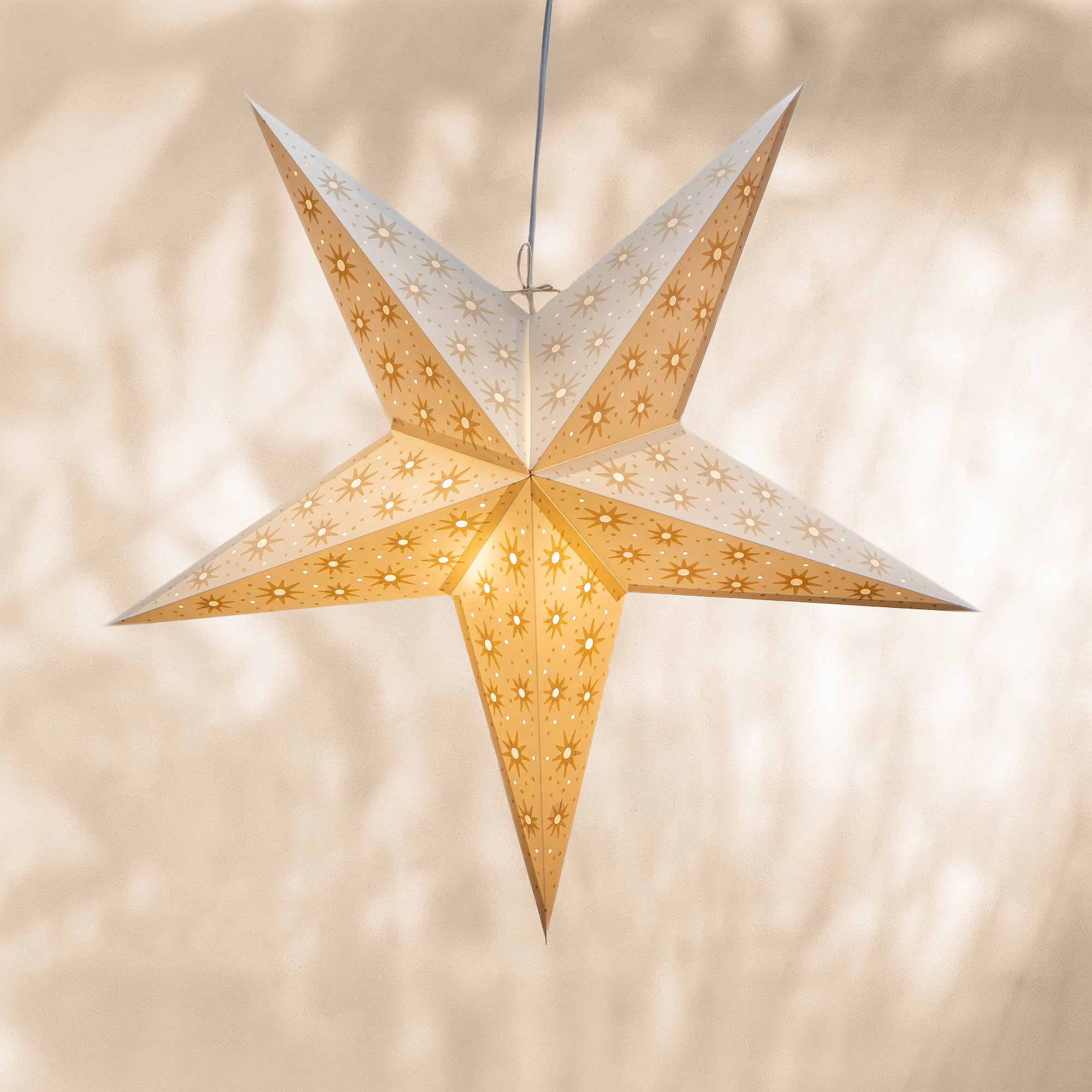 Star-shaped paper lantern with cut-out patterns on a beige background