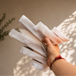 Hand holding a stack of white cylindrical objects against a beige wall with shadows.