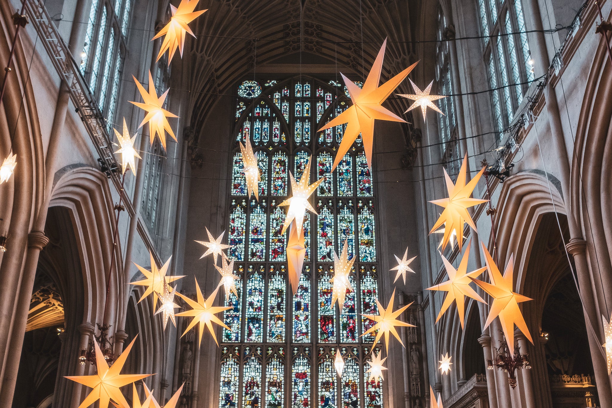 Illuminated Light of Stars installation framed by stained glass at Bath Abbey