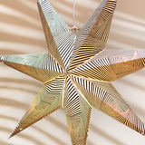Decorative star-shaped object with gold and silver stripes on a beige background