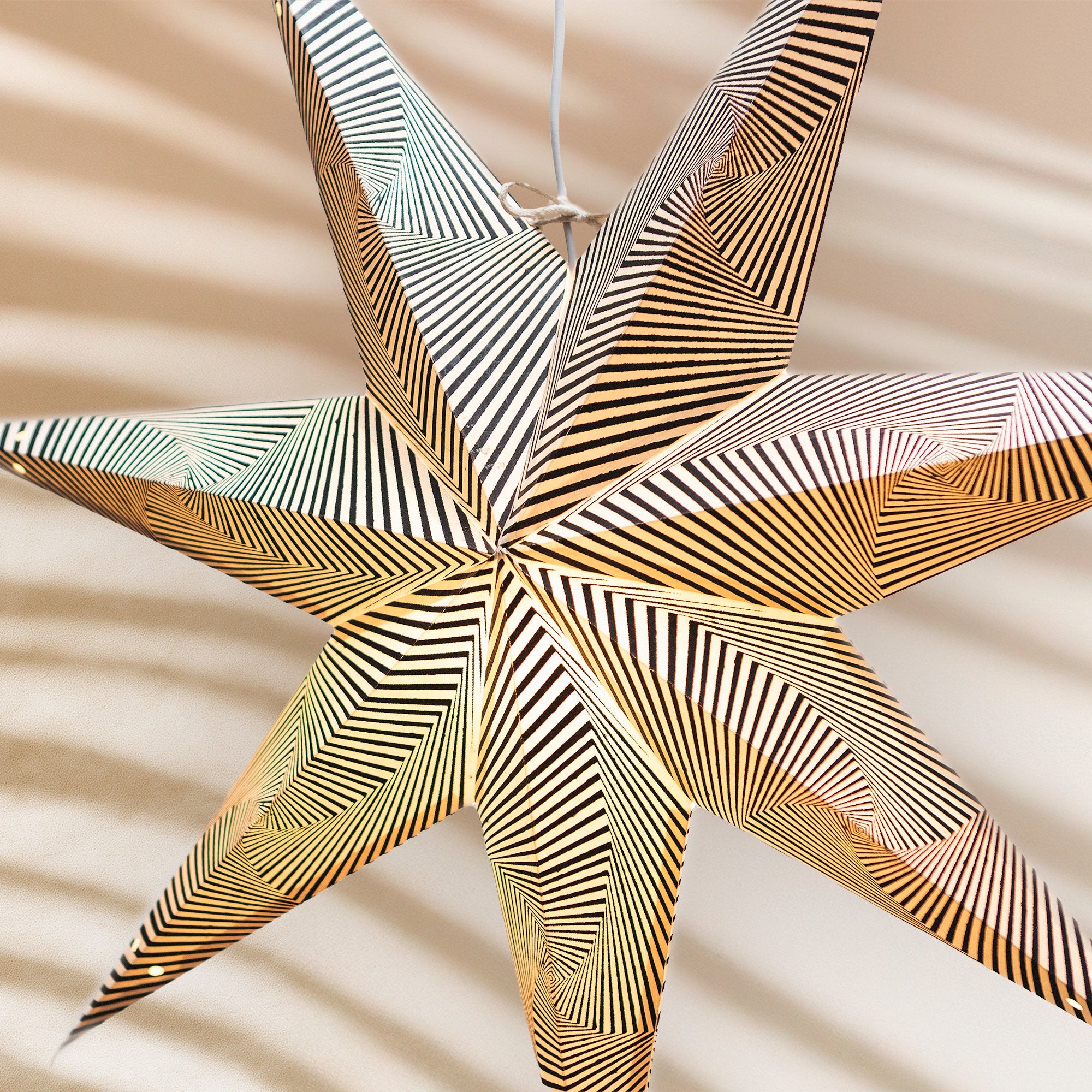 Decorative star-shaped object with gold and silver stripes on a beige background