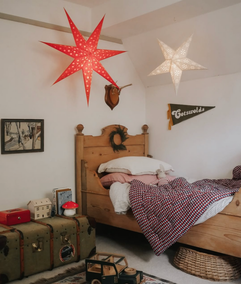 Children's bedroom with wooden bed, star-shaped lights, and vintage decor.