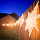 Decorative star lights on a wooden fence with a clear blue sky.
