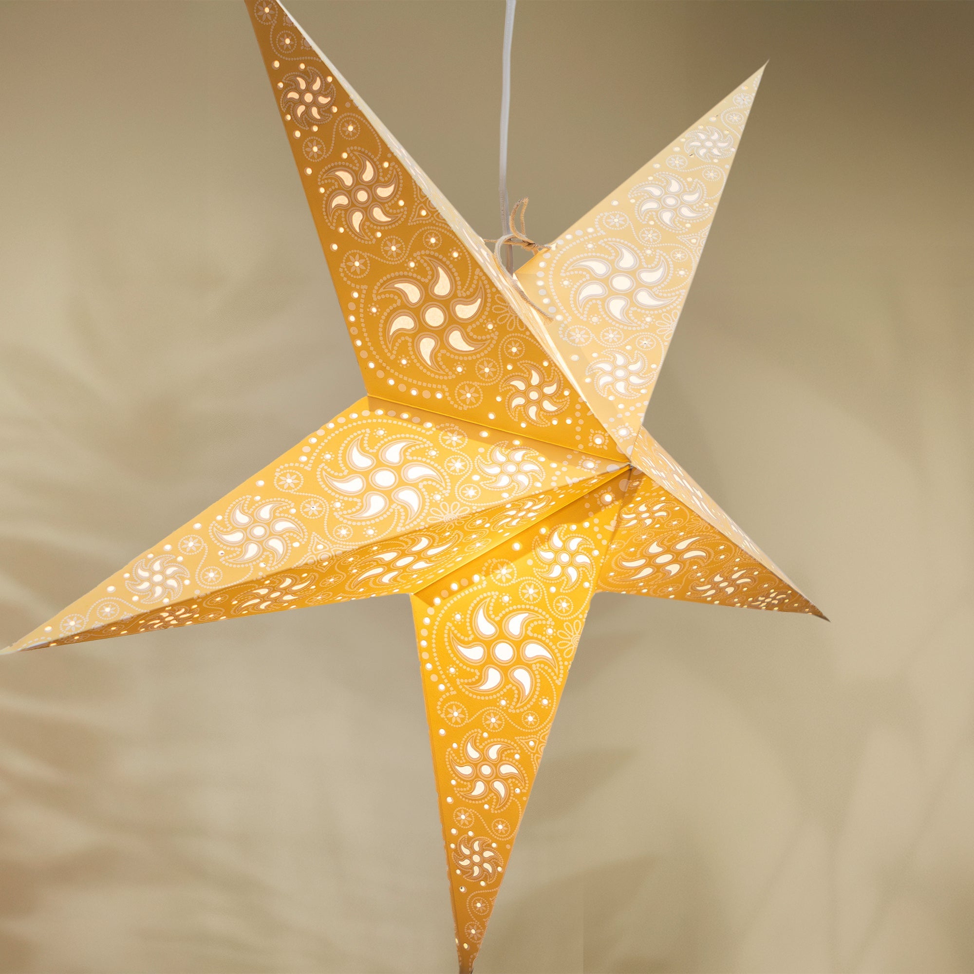 Decorative star-shaped lamp with cut-out patterns on a neutral background