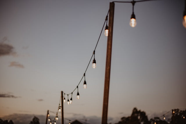 String of outdoor lights hanging from a wooden post against a twilight sky.