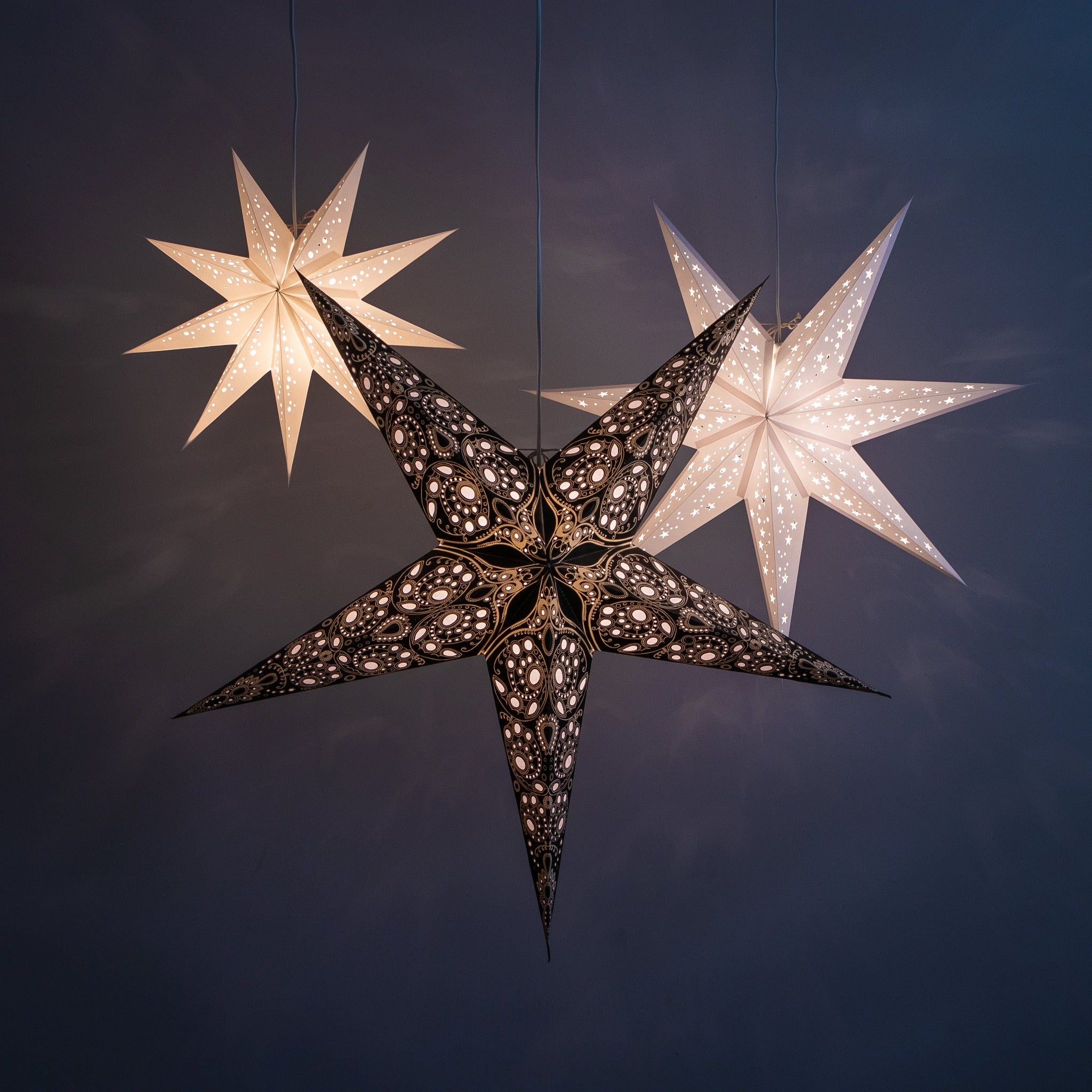 1 small white, 1 white and 1 black/white star lantern illuminated 